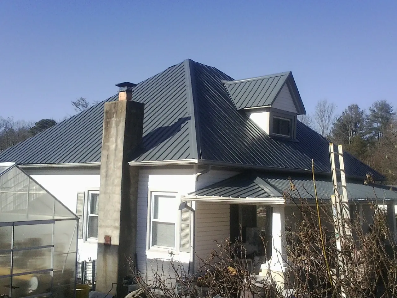 Dark blue standing seam metal roof on a white farmhouse with dormer — Slate & Tile Roof Repair by Roofing Brothers in Southport