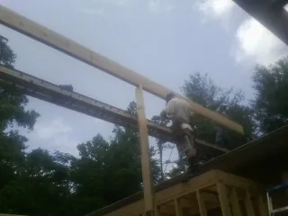 Carpenter setting a ridge beam over a new addition frame — Ice Dam Removal by Roofing Brothers in Southport