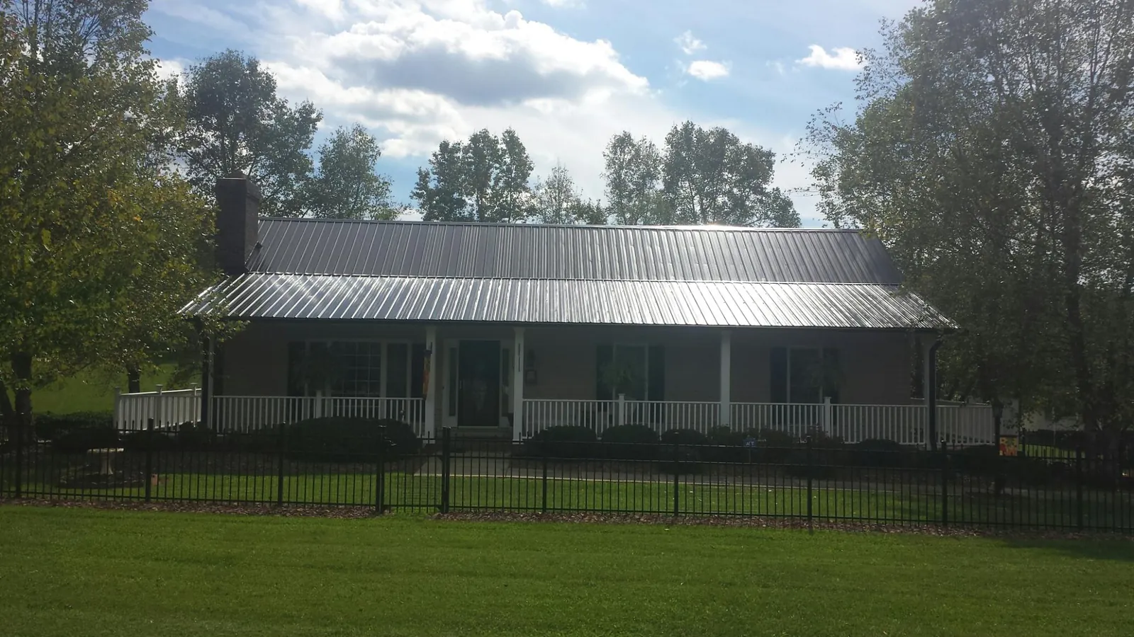 Gray metal roof on a brick ranch with a full width front porch — Gutter Guard Installation work by our crew in Southport