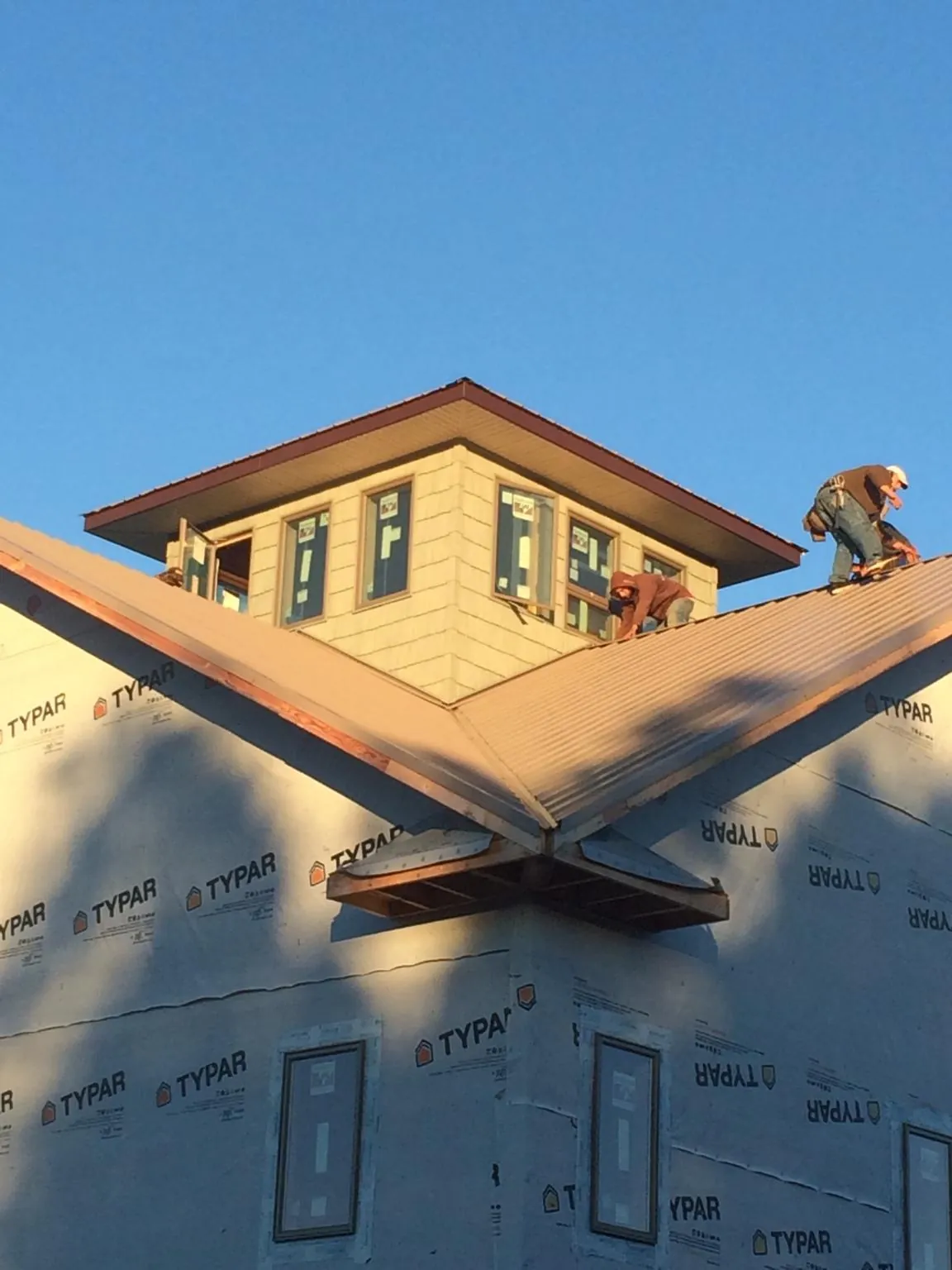 Roofers working around a rooftop cupola on a new metal roof at sunset — Roof Waterproofing in Southport by Roofing Brothers